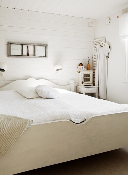 Drewniane bielone łóżko,stolik nocny i ramki w prowansalkim stylu w sypialni