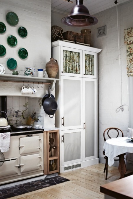 Biała kuchnia w stylu vintage z retro piecem, i turkusowymi talerzami na ścianie