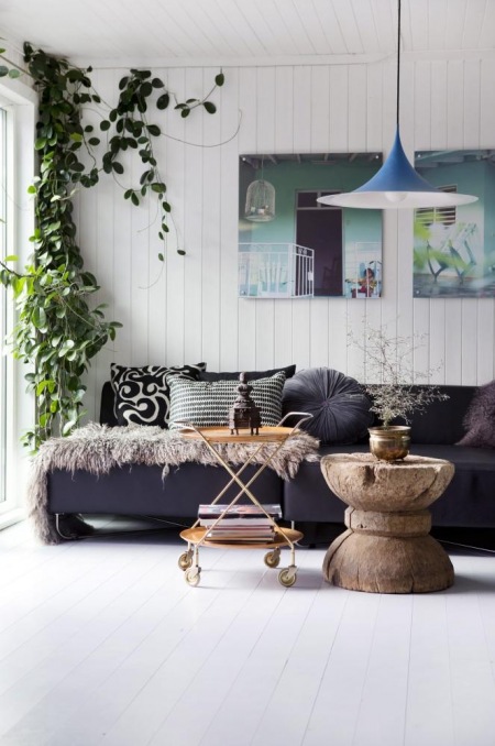 Czarna sofa,nowoczesne malarstwo,niebieska lampa i dizajnerski stolik z drewnianego pieńka