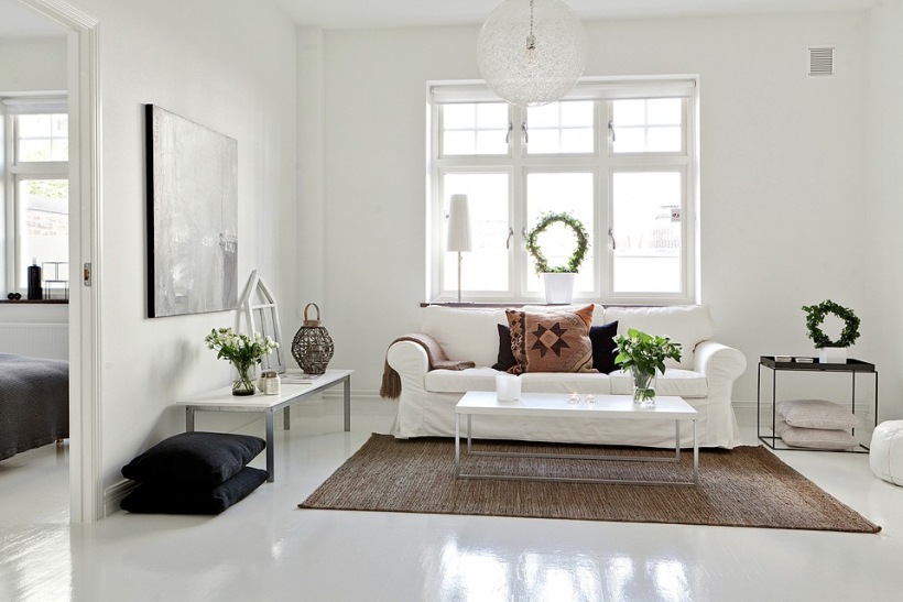 Biała sofa,jutowy dywan i czarne poduszki w salonie