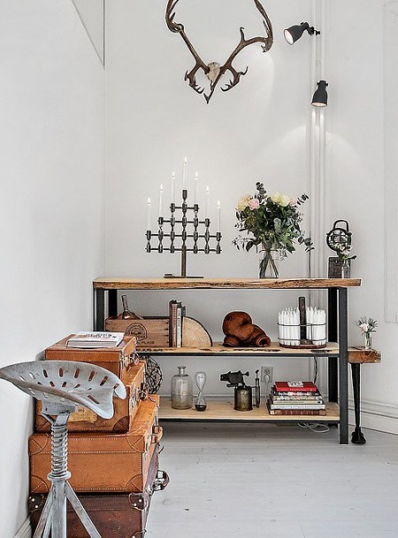 Dekoracyjne walizki vintage,industrialny stołek i metalowo-drewniane półki w salonie
