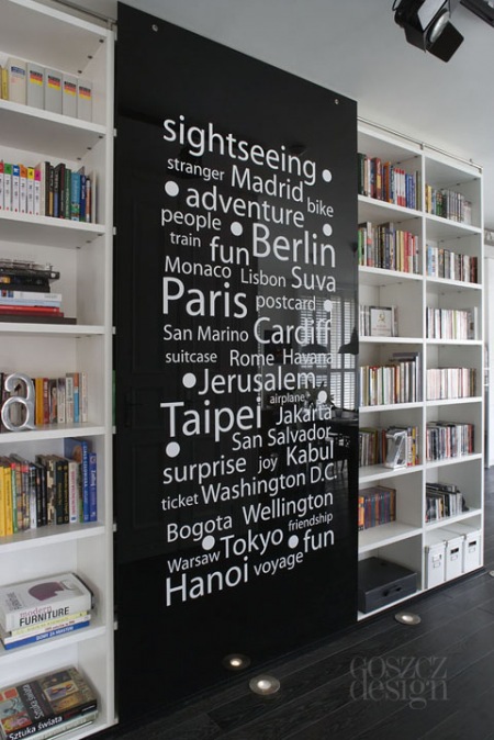 Szklane czarne ścianki przesuwane z  białą typografią przy domowej biblioteczce