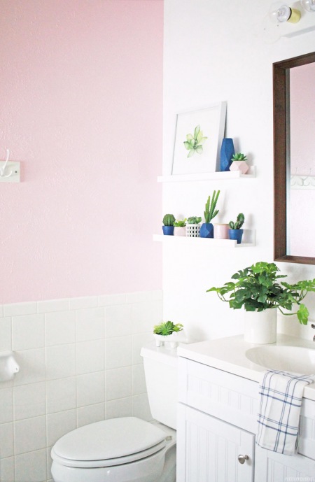 Zielone rośliny i granatowe doniczki w pastelowej łazience