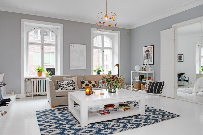 Biały stolik kawowy z półka,beżowa sofa,niebiesko-biały dywan i szare ściany w aranżacji salonu skandynawskiego