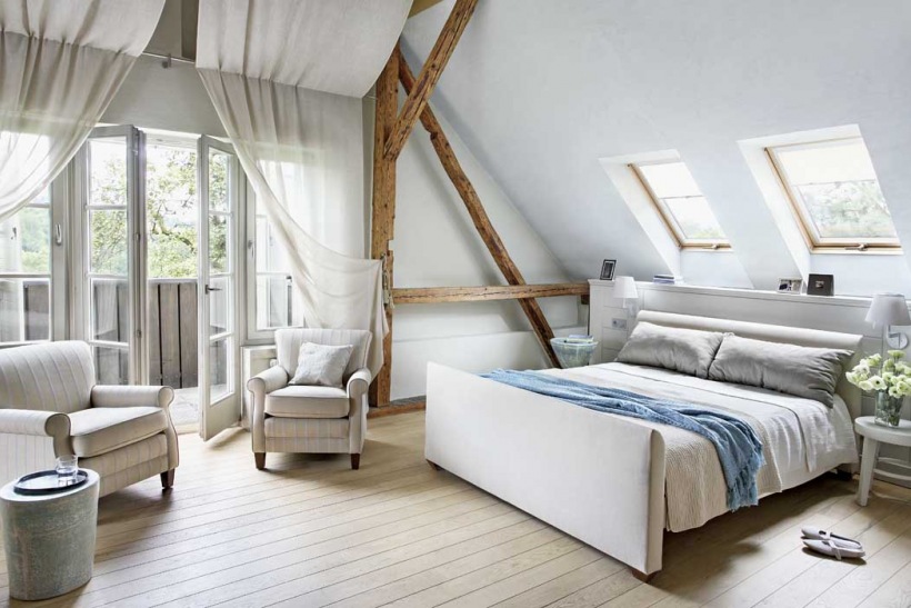 Pomysłowe zasłony w białej sypialni z tapicerowanym łóżkiem i drewnianymi belkami