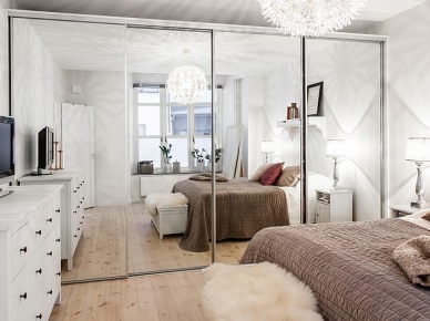 Biała sypialnia z lustrzaną szafą, białą komodą i beżowo-różową dekoracją łóżka (21849)