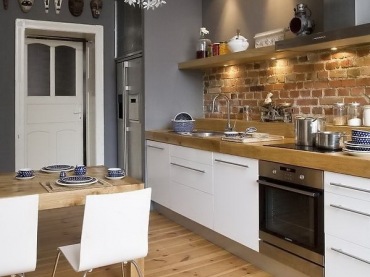 Nowoczesna biała kuchnia z detalami ze stali,szarymi i ceglanymi ścianami i drewnianą podłogą (25276)