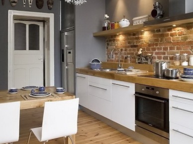 Nowoczesna biała kuchnia z detalami ze stali,szarymi i ceglanymi ścianami i drewnianą podłogą (25276)