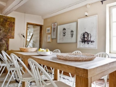 Prosty rustykalny stół z naturalnego drewna,białe skandynawskie krzesła,nowoczesne grafiki na scianach w jadalni z bielonymi belkami z drewna (24957)