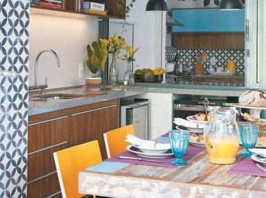 Przecierany stół w kolorowej kuchni, gdzie żółte i błękitne dodatki dodają energicznej...