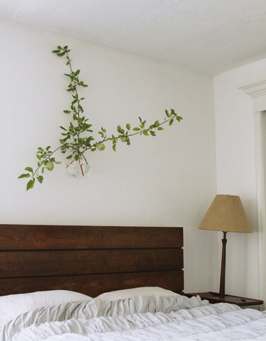 Wiszący wazon z zieloną rośliną nad łóżkiem z drewnianym wezgłowiem z desek