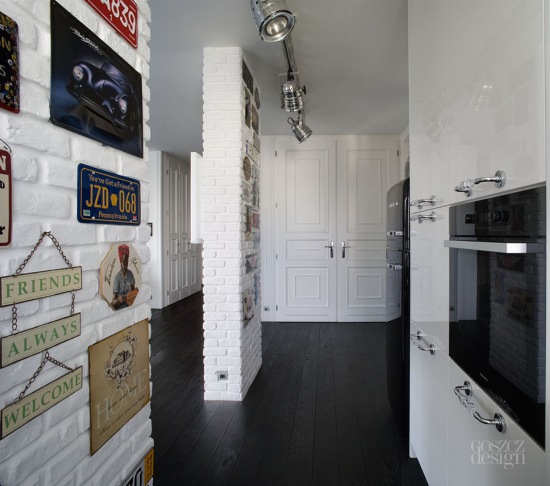 Biała lakierowana kuchnia ze ścianami z białej cegły i galerią metalowych tabliczek w stylu retro i vintage