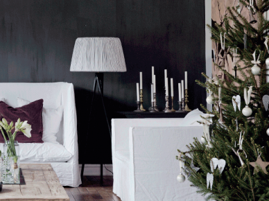 Białe sofy i fotele w lnianych pokrowcach,czarna ściana,stolik z palety na kółkach,zielona choinka w białych dekoracjach świątecznych (47764)