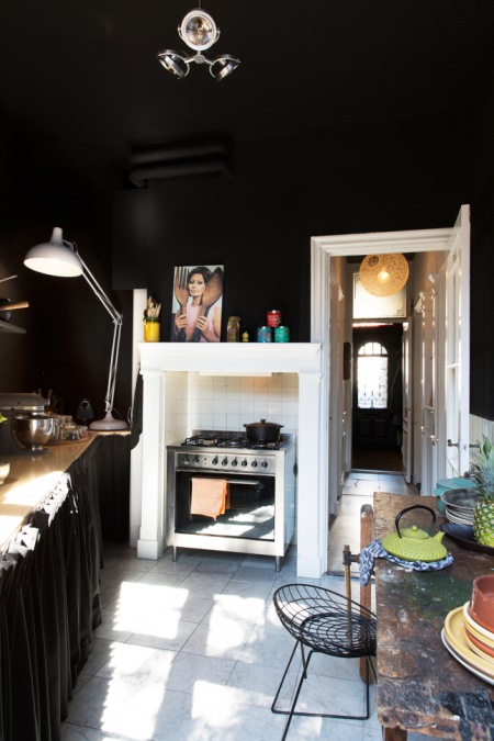 Czarne ściany w aranzacji industrialnej kuchni z drucianymi krzesłami i postarrzanym stołem vintage