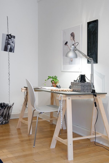 Surowe drewniane biurko, srebrna lampa i metalowe białe krzesło