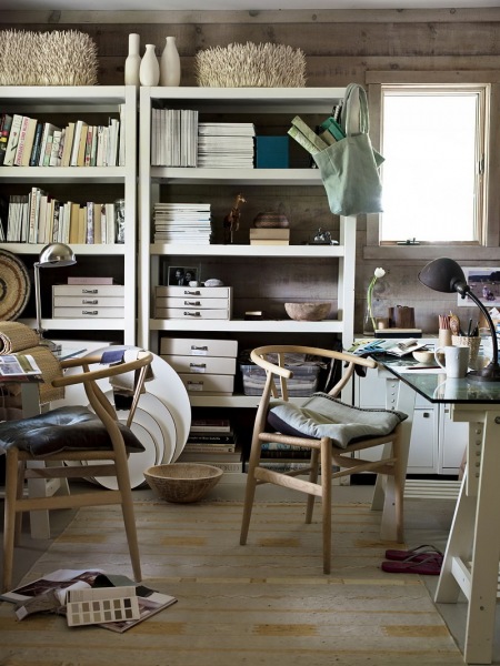 Skandynawskie gięte krzesła z drewna,białe regały z otwartymi pólkami i stolik na kozłach ze szklanym blatem w pokoju biurowym