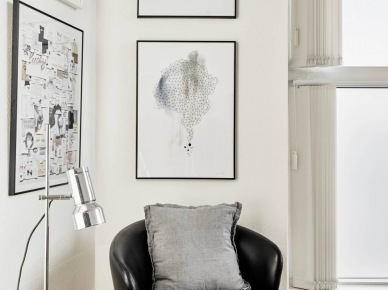 Nowoczesne biało-czarne grafiki,czarny skórzany fotel ,srebrna lampa biurkowa i biały stolik z tacą (26860)