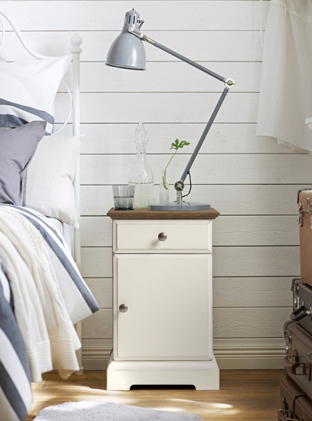 Szara lampka nocna na przegubach,nocny stolik z szufladą i białe panele z drewna na ścianie w sypialni