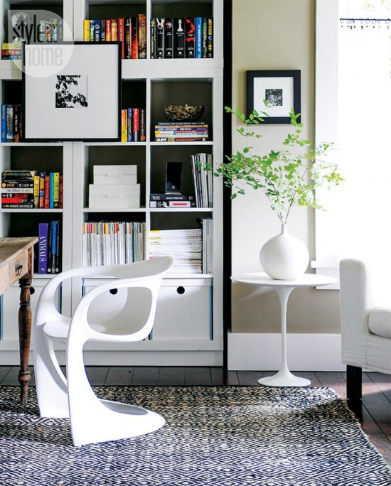 Drewniany rustykalny stół z drewna,biały nowoczesny fotelik z tworzywa,okrągły biały stolik pomocniczy i nowoczesny regał z książkami