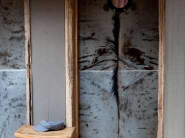 Pomysłowe drzwi z drewna i szarego futerka z metalowym okragłym okienkiem w korytarzu z szarymi ścianami (27680)