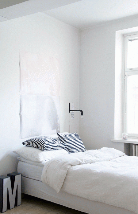 Biała sypialnia w minimalistycznym skandynawskim stylu z industrialnym kinkietem i szarą literą 3d