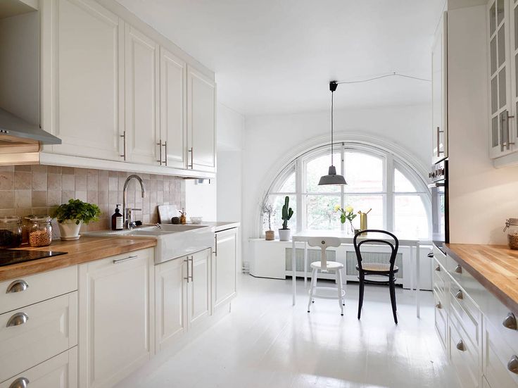 Biała kuchnia skandynawska z białą podłogą i półokrągłym oknem