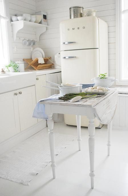 Biała kuchnia w tradycyjnym skandynawskim stylu z białą  lodówką Smeg