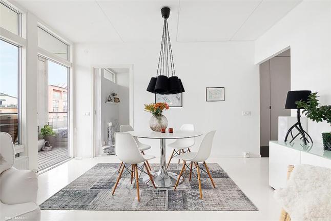 Szaro-biały dywan vintage,okrągły biały stół,krzesła vitra i czarne nowoczesne lampy