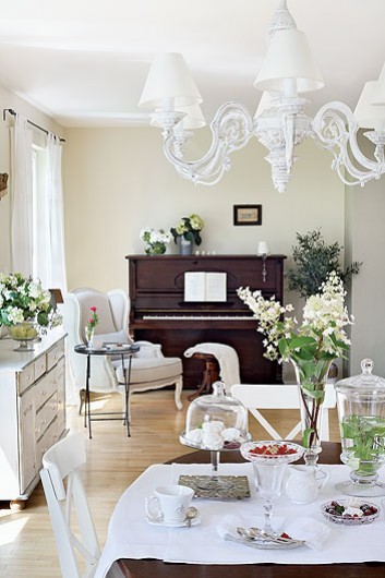 Francuskie białe meble  i żyrandol i brązowe drewniane pianino w salonie