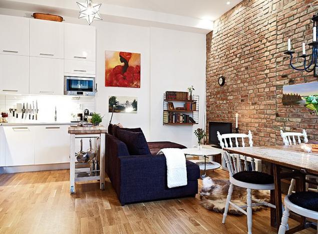Pomysl na otwartą przestrzeń małego mieszkania z ceglaną ścianą
