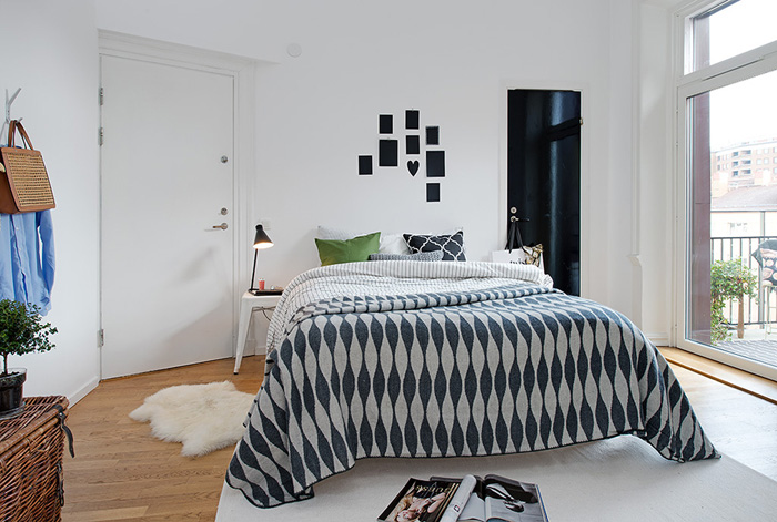 Aranżacja skandynawskiej sypialni z szaro-białą narzutą na łóżku