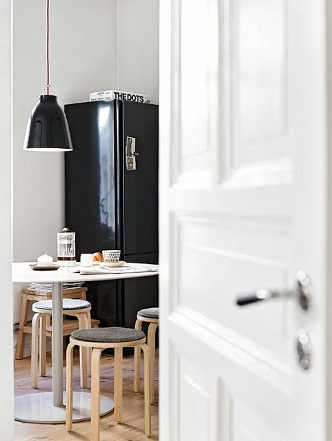 Drewniane stołki i czarna lodówka z lampą w kuchni