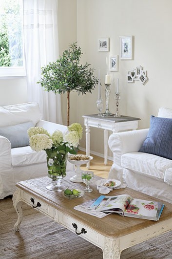 Prowansalski stolik kawowy,biały stolik pomocniczy,biała sofa i stylowe świeczniki w salonie