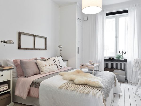 Skandynawska sypialnia z futrzakiem i poduszkami w pastelowych kolorach