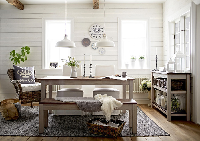 Białe lampy metalowe,drewniany stół,ławka, konsolka z półkami i wiklinowy fotel w aranżacji jadalni