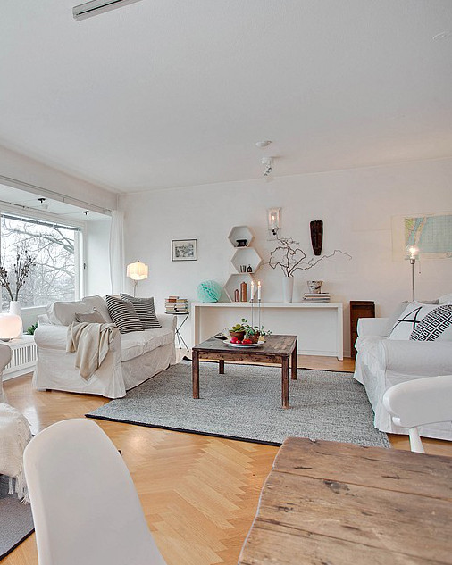 Aranżacja salonu w stylu skandynawskim z białymi sofami i szarym dywanem