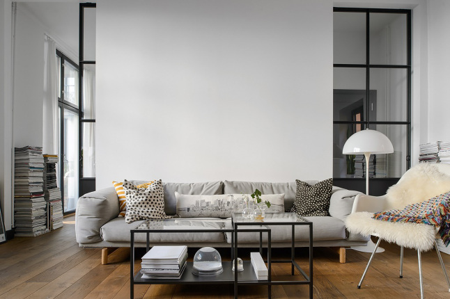 Metalowe ramy ścian ze szkłem,metalowe stoliki industrialne i szara sofa w aranżacji salonu w stylu industrialnym