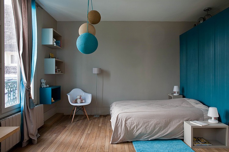 Szara ściana,drewnian podłoga i turkusowa zabudowa szaf w nowoczesnej sypialni