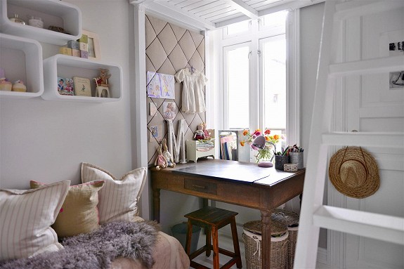 Białe półki kubikowe,pikowana ściana,stylowe biurkowi wiklinowe kosze w dziecięcym pokoju