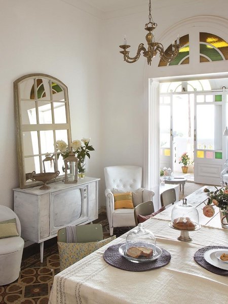 Żyrandol z mosiądzu,lusrro okno,bielona stylowa komoda,białe tapicerowane fotele