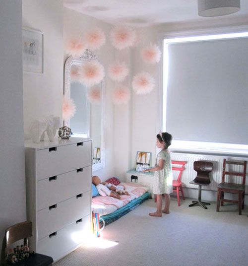 Jasno-różowe tiulowe pompony w dekoracji białego pokoju dla dziewczynki