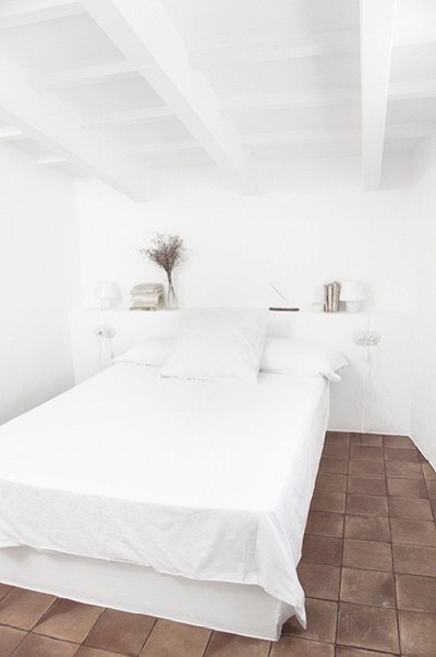 Biała sypialnia z terakotową posadzką