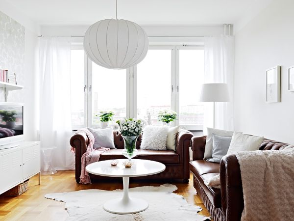 Stylowe skórzane sofy w białym skandynawskim salonie z nowoczesnymi meblami
