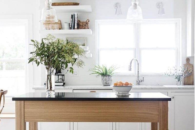 Drewniany stół jako wyspa kuchenna w białej kuchni