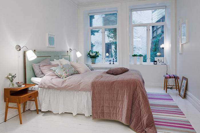 Biała  sypialnia z turkusowym łóżkiem,różową narzutą i dywanikiem utkanym w paski