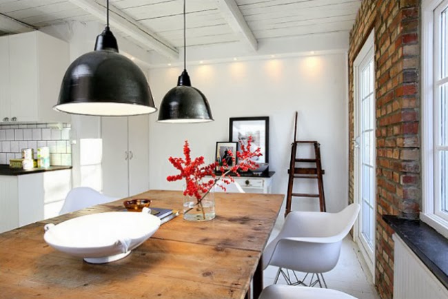 Czarne emaliowane lampy,drewniany industrialny stół,nowoczesne krzesła i ściana z czerwonej cegły