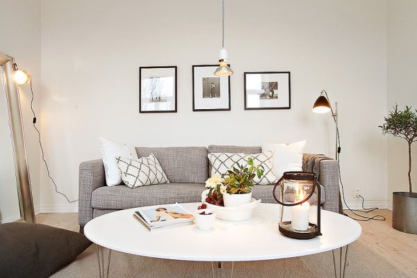 Szara sofa,żarówka na kablu i biały owalny stolik w salonie