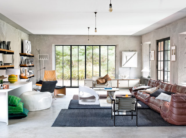 Skórzana sofa,wiszące półki i nowoczesne meble w jednym salonie