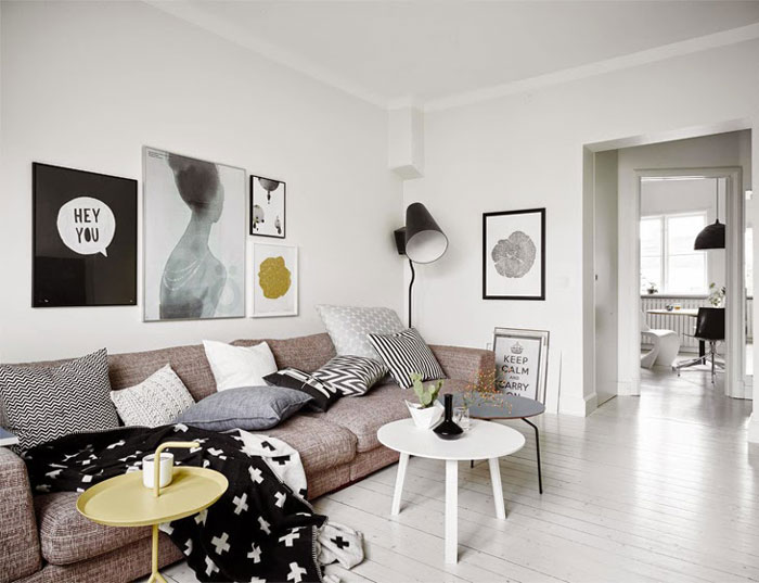 Nowoczesna fotografia i grafiki na ścianie w białym salonie skandynawskim z beżową sofą i białymym, szarym i zielonkawym stolkikiem okrągłym