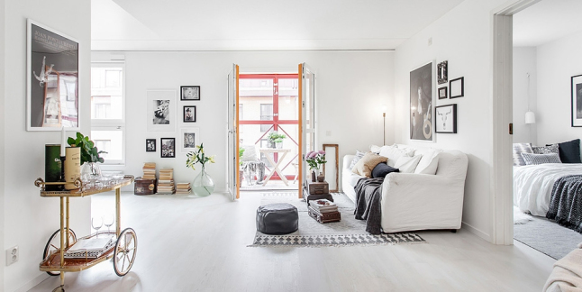 Czarny skórzany puf,barek vintage na kółkach,biało-czarny dywan w stylu skandynawskim i galeria fotografii na ścianach w salonie